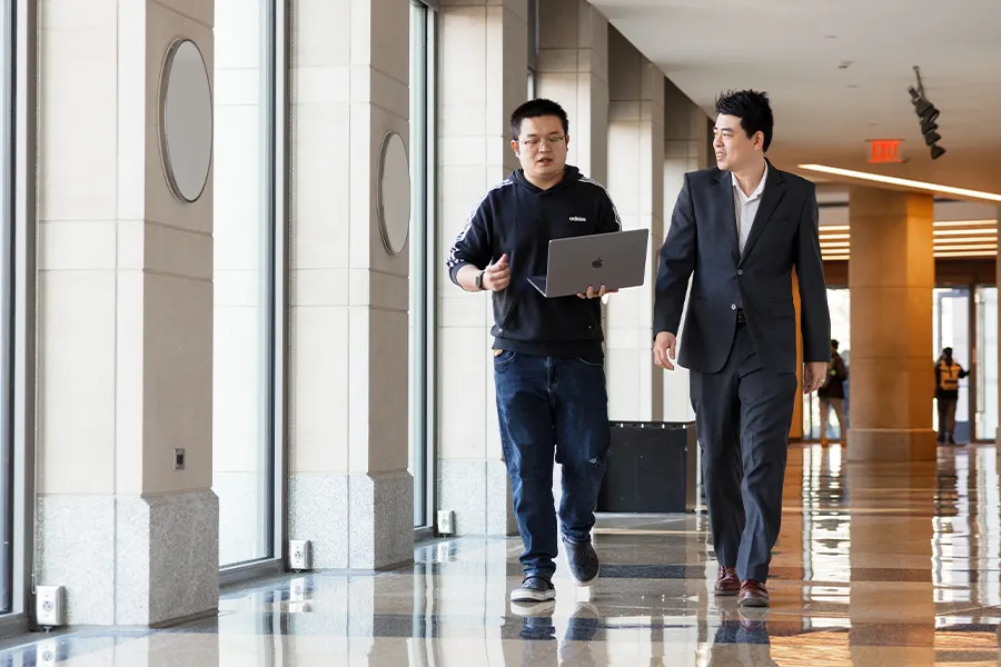 A man in casual wear carrying a laptop has a deep conversation with a businessman. 